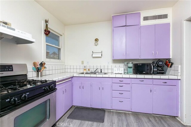 13115 Davenport St, North Edwards, CA 93523 - kitchen with stainless steel range with gas cooktop, a sink, under cabinet range hood, light wood-style floors, and tile countertops