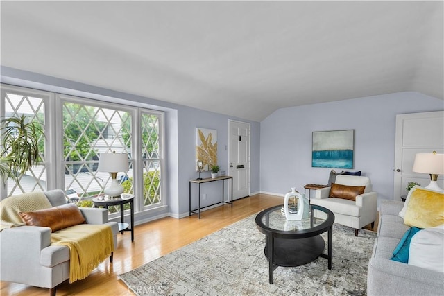 living room featuring a healthy amount of sunlight, light hardwood / wood-style flooring, and vaulted ceiling