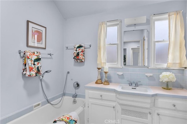 bathroom with a washtub, vanity, a wealth of natural light, and backsplash