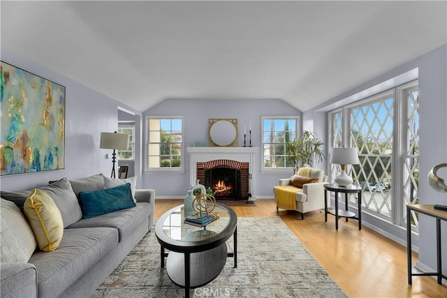 living room featuring light hardwood / wood-style floors, a fireplace, and vaulted ceiling