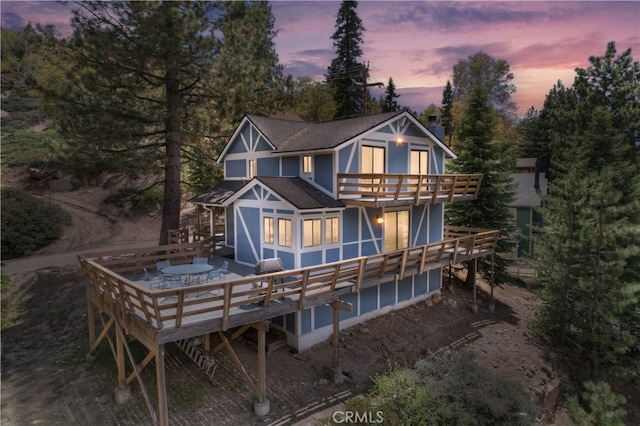 back house at dusk featuring a wooden deck