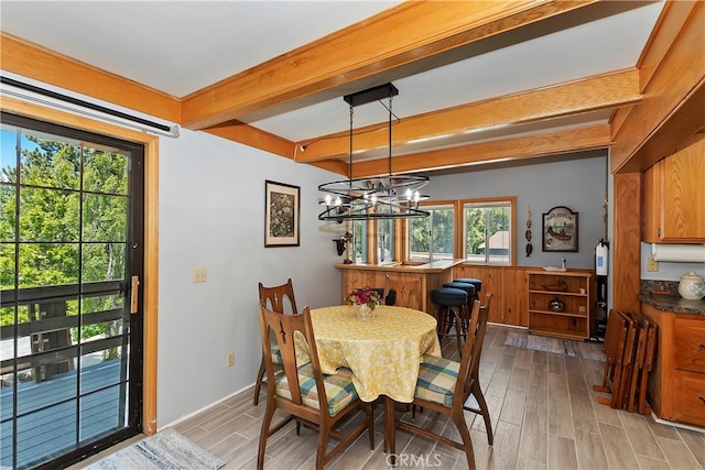 dining space featuring a notable chandelier, beam ceiling, and light wood-type flooring