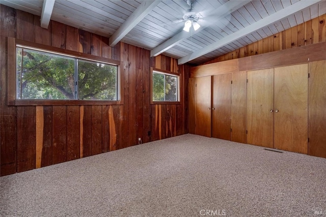 carpeted spare room with wood ceiling, wood walls, plenty of natural light, and ceiling fan