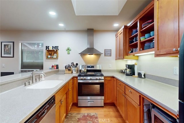 kitchen with appliances with stainless steel finishes, light hardwood / wood-style floors, wall chimney exhaust hood, and sink