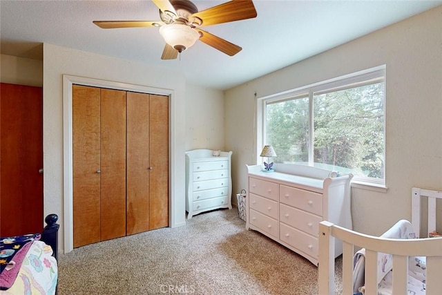 carpeted bedroom with ceiling fan and a closet