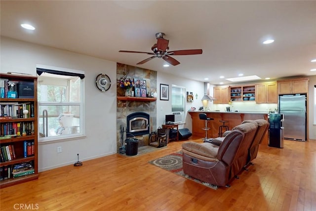 living room with light wood-type flooring, a wood stove, and ceiling fan