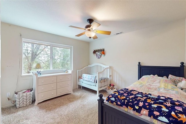 carpeted bedroom with ceiling fan and a textured ceiling