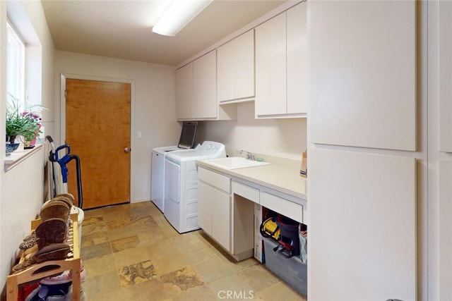 clothes washing area with washer and clothes dryer, cabinets, and sink