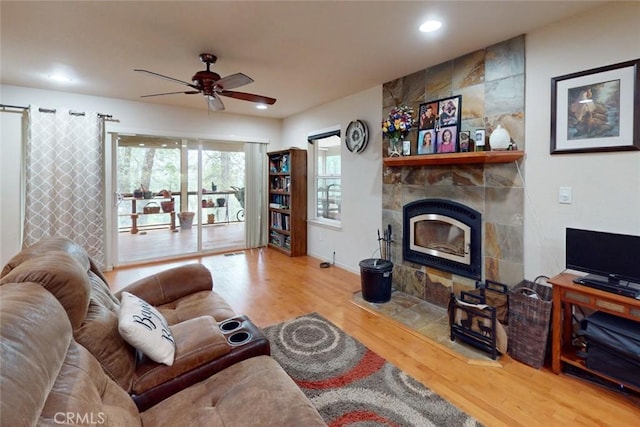 living room with ceiling fan, a fireplace, and wood-type flooring