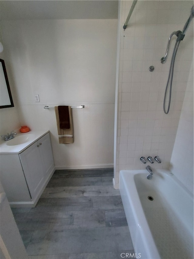 bathroom with hardwood / wood-style flooring, tiled shower / bath combo, and large vanity