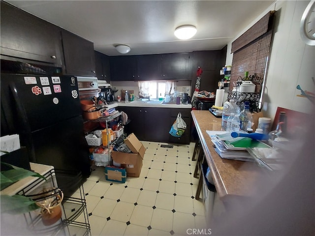 kitchen with black fridge and light tile floors