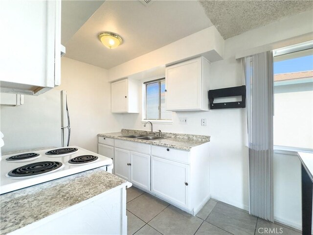 kitchen featuring white cabinetry, range with electric cooktop, sink, and light tile patterned floors