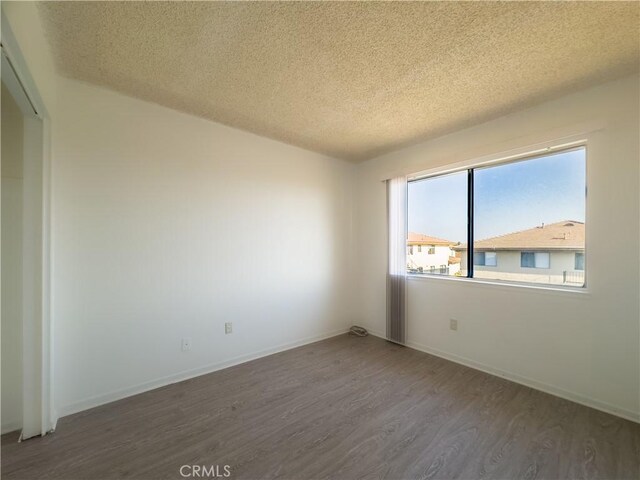 unfurnished room with dark wood-type flooring and a textured ceiling