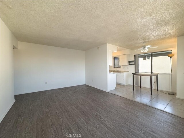 unfurnished living room with ceiling fan, a textured ceiling, and light hardwood / wood-style floors