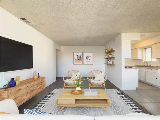 living room featuring dark tile patterned flooring, sink, and a textured ceiling