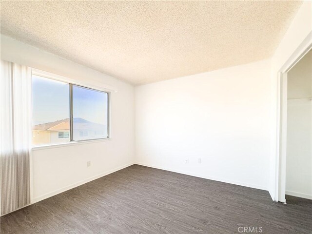 spare room with dark hardwood / wood-style floors and a textured ceiling