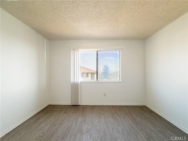 unfurnished room with hardwood / wood-style floors and a textured ceiling