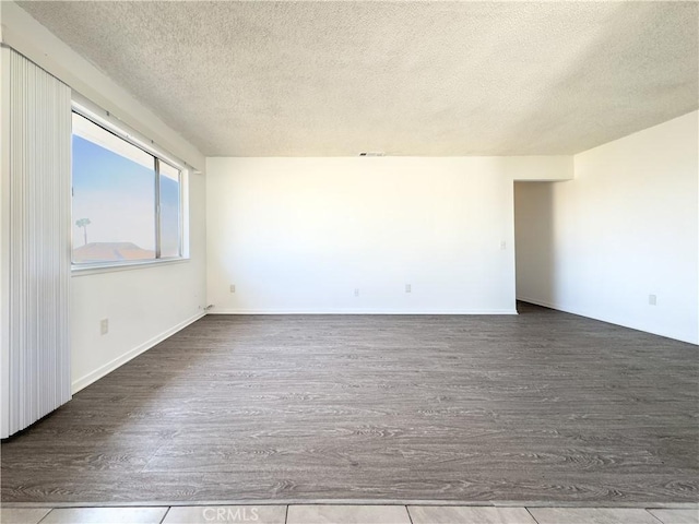 empty room with hardwood / wood-style floors and a textured ceiling