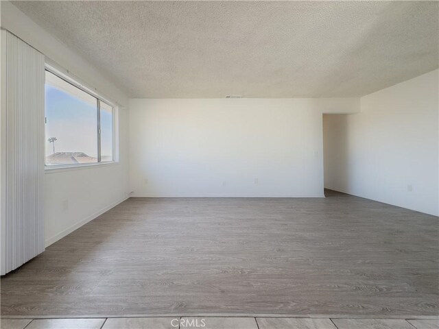 unfurnished room with light hardwood / wood-style flooring and a textured ceiling