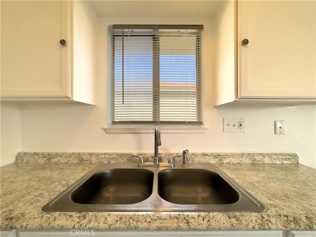 details with white cabinetry, sink, and light stone counters