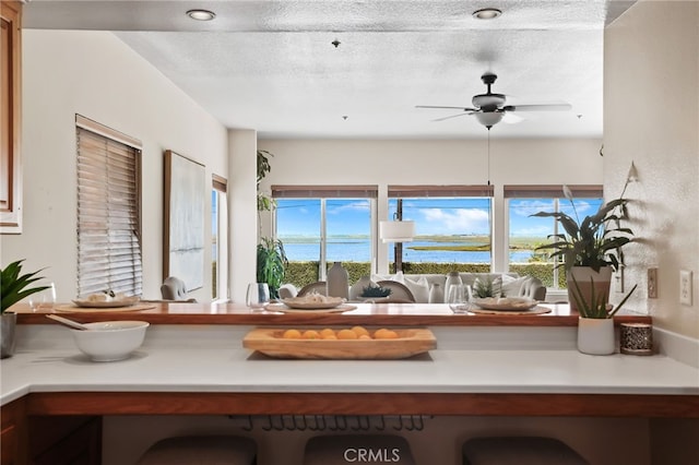 interior space featuring a textured ceiling, a water view, and ceiling fan