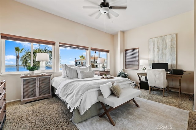 bedroom with carpet, ceiling fan, and a water view