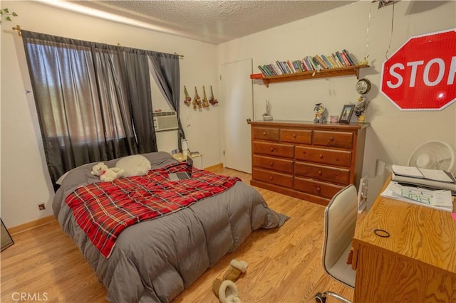 bedroom featuring a textured ceiling, light wood-type flooring, and cooling unit