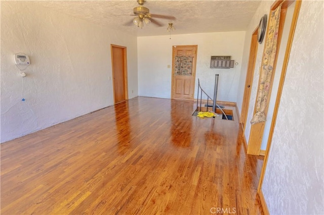 empty room featuring ceiling fan, a textured ceiling, and hardwood / wood-style flooring