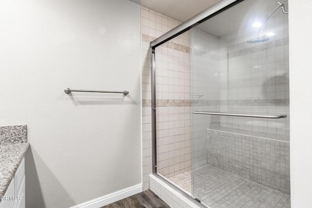 bathroom with wood-type flooring, vanity, and a shower with door