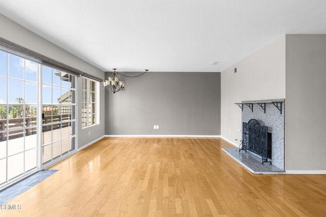 unfurnished living room featuring a fireplace, hardwood / wood-style floors, and a chandelier