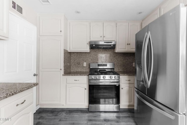 kitchen featuring appliances with stainless steel finishes, dark hardwood / wood-style floors, white cabinetry, and dark stone counters