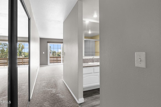 hallway featuring dark carpet and sink