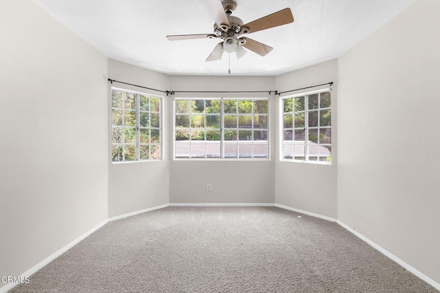 carpeted spare room featuring ceiling fan and a healthy amount of sunlight