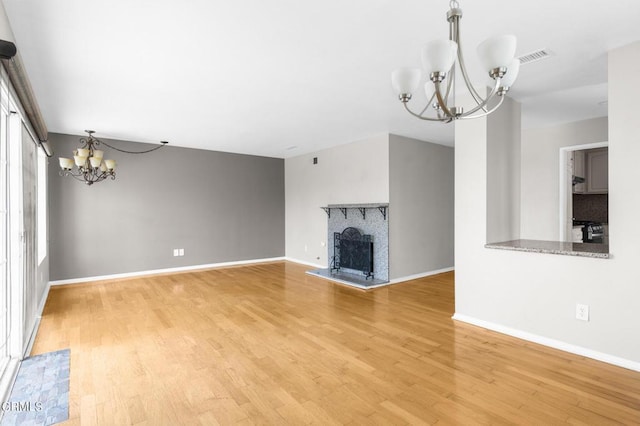 unfurnished living room with a chandelier, wood-type flooring, and a brick fireplace