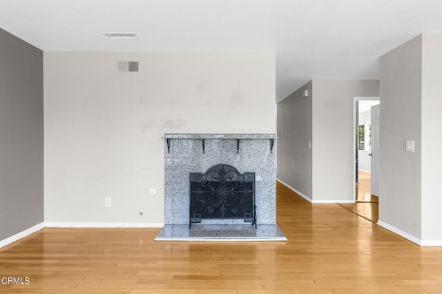 unfurnished living room featuring a tile fireplace and wood-type flooring