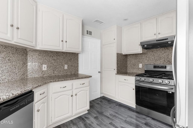 kitchen featuring decorative backsplash, stainless steel appliances, dark stone countertops, dark hardwood / wood-style floors, and white cabinetry