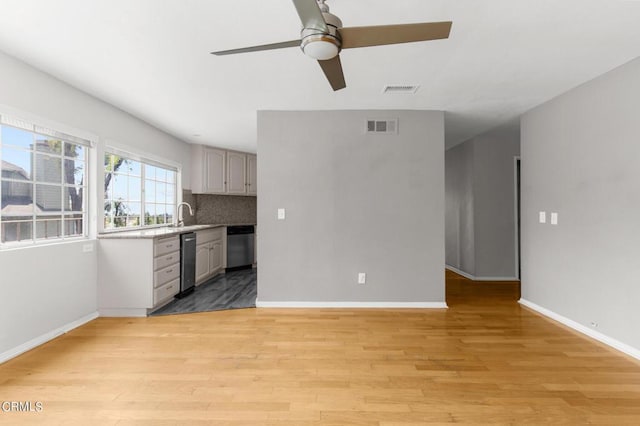 kitchen featuring gray cabinetry, ceiling fan, dishwasher, backsplash, and light hardwood / wood-style floors