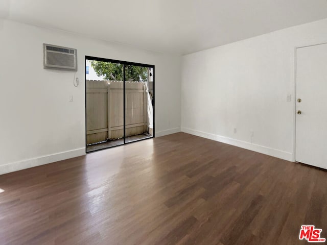 empty room featuring dark wood-type flooring and a wall mounted AC