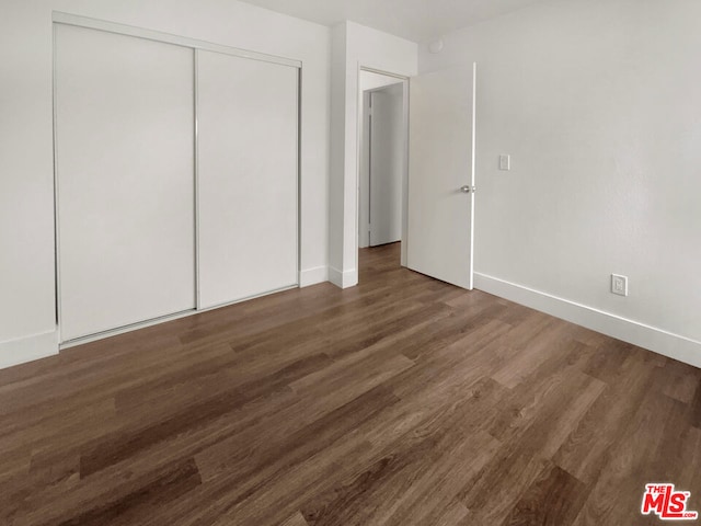 unfurnished bedroom featuring dark hardwood / wood-style floors and a closet