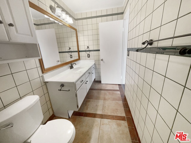 bathroom with vanity, toilet, and tile walls