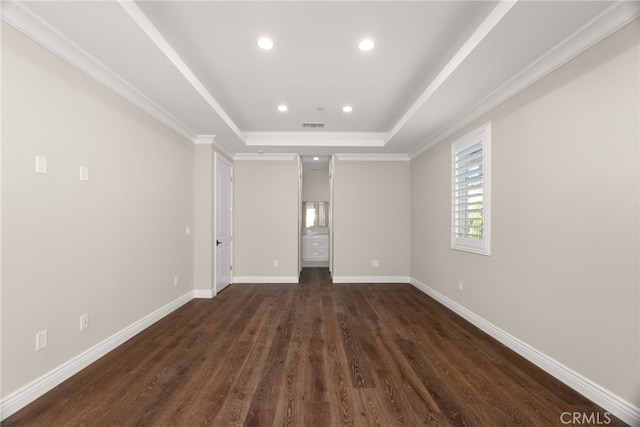 empty room featuring crown molding, dark wood-type flooring, and a tray ceiling