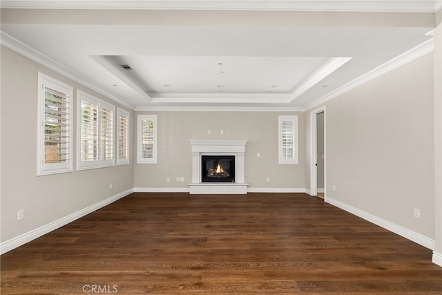 unfurnished living room with a tray ceiling, dark hardwood / wood-style floors, and ornamental molding