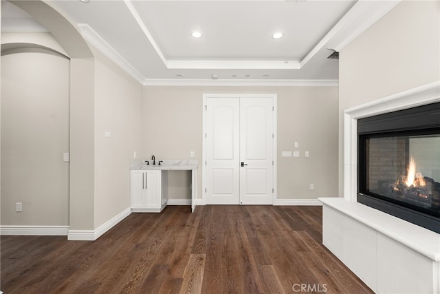 interior space featuring a tray ceiling, crown molding, dark wood-type flooring, and sink