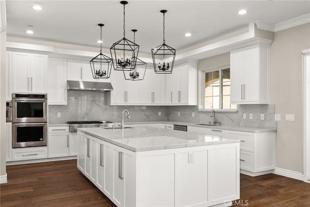 kitchen with light stone countertops, a center island with sink, white cabinets, and sink