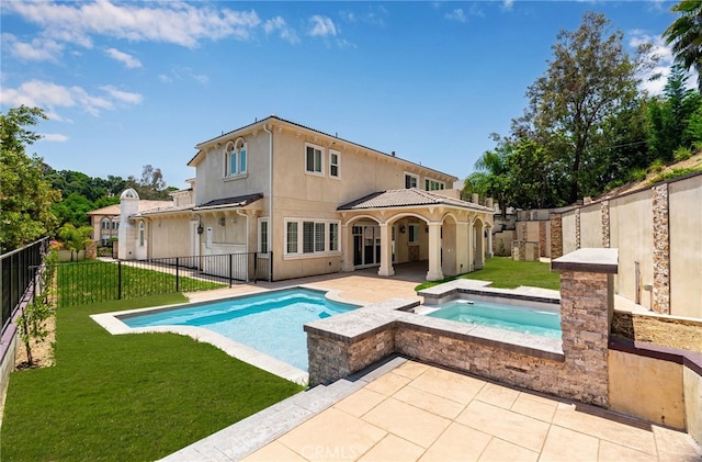 rear view of property featuring a lawn, a patio area, and a pool with hot tub