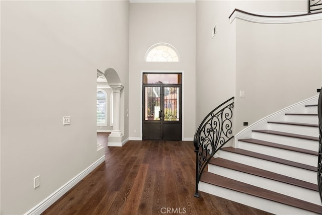 entryway featuring ornate columns, a towering ceiling, and dark hardwood / wood-style floors