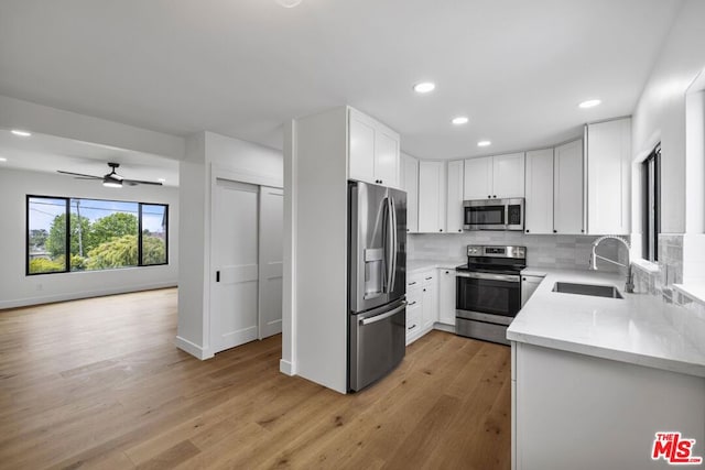 kitchen with ceiling fan, light hardwood / wood-style floors, backsplash, and appliances with stainless steel finishes