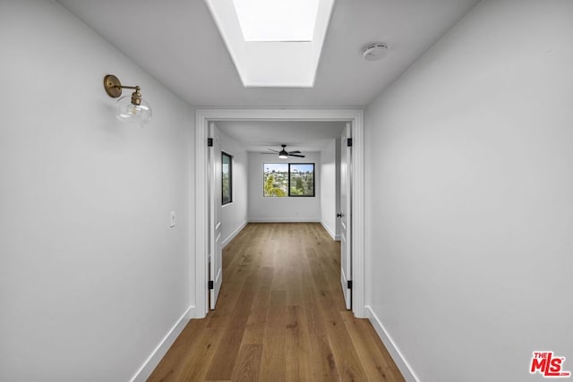 hallway featuring hardwood / wood-style flooring and a skylight