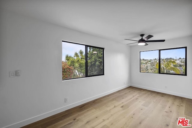 empty room featuring plenty of natural light, light wood-type flooring, and ceiling fan