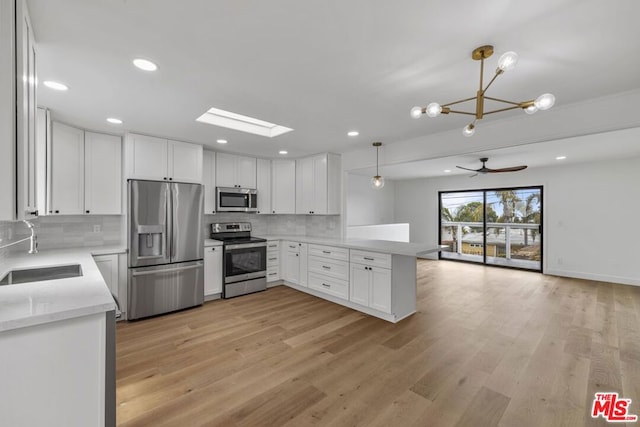 kitchen with stainless steel appliances, sink, light hardwood / wood-style flooring, and pendant lighting